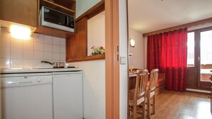 A compact kitchen with a dishwasher, microwave, and wooden cabinets.
