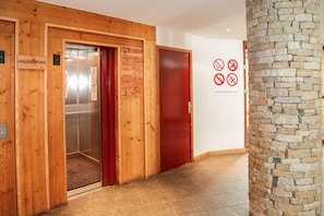 Welcome to our hotel lobby, featuring a stone column and clear directions to the elevator and reception.