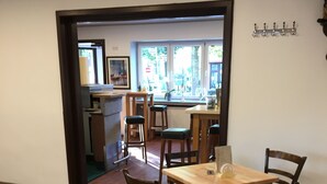 Un restaurante con mesas y sillas de madera, una zona de bar y vistas a la calle a través de amplios ventanales.