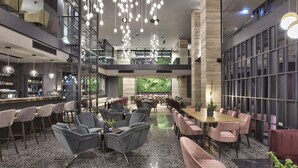 A modern hotel lobby with a bar area, seating arrangements, and a large glass wall with a green view. - Number 11 St Julian's Malta - Handwritten Collection (St. Julian's)