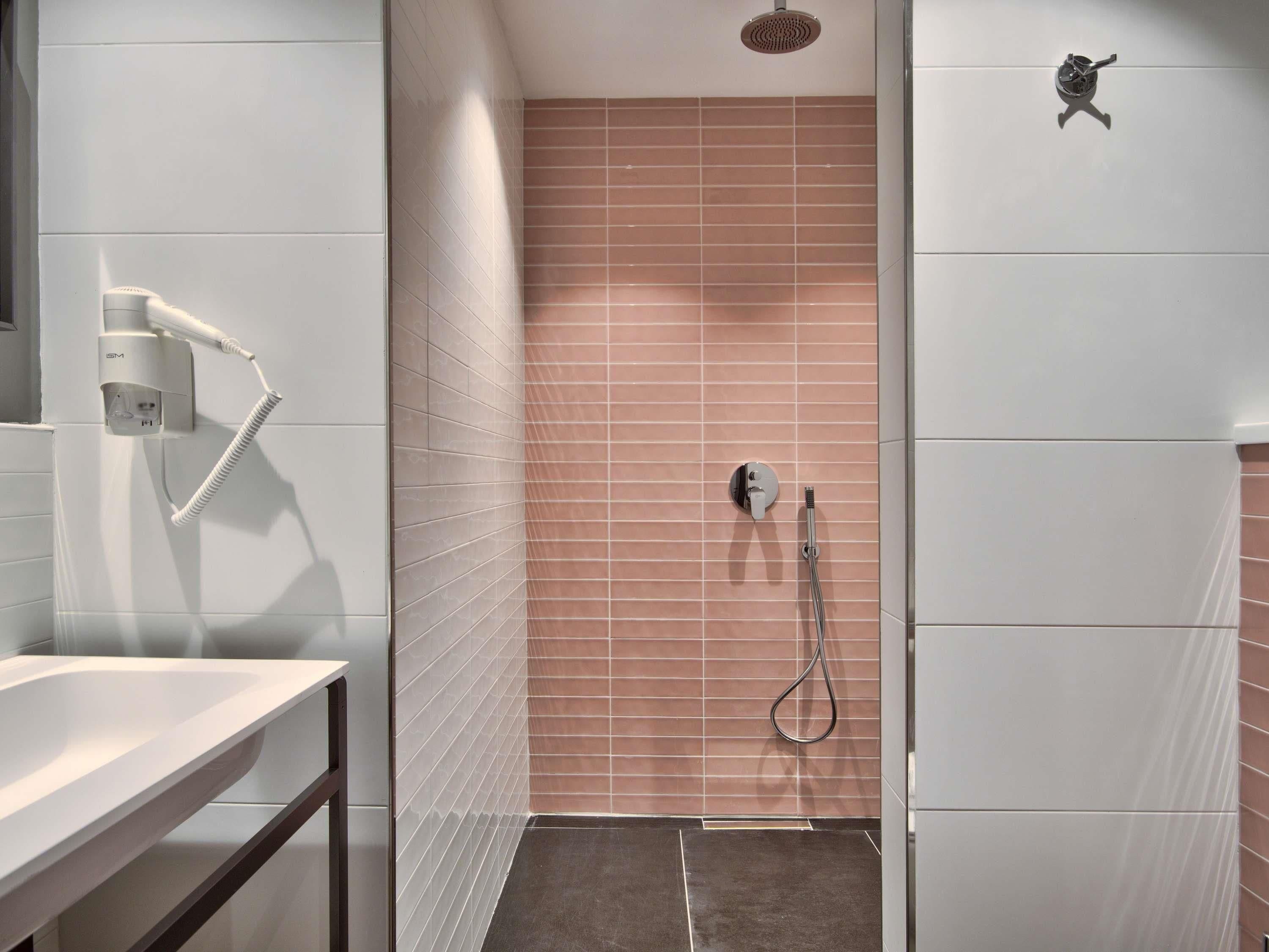 Un espace douche équipé d’un pommeau de douche à main et d’un panneau de commande fixé au mur.