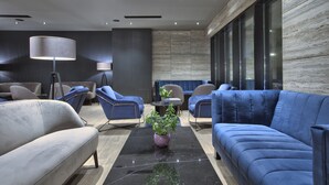 A modern lobby with a sofa, chairs, a coffee table, and a lamp. - Number 11 St Julian's Malta - Handwritten Collection (St. Julian's)