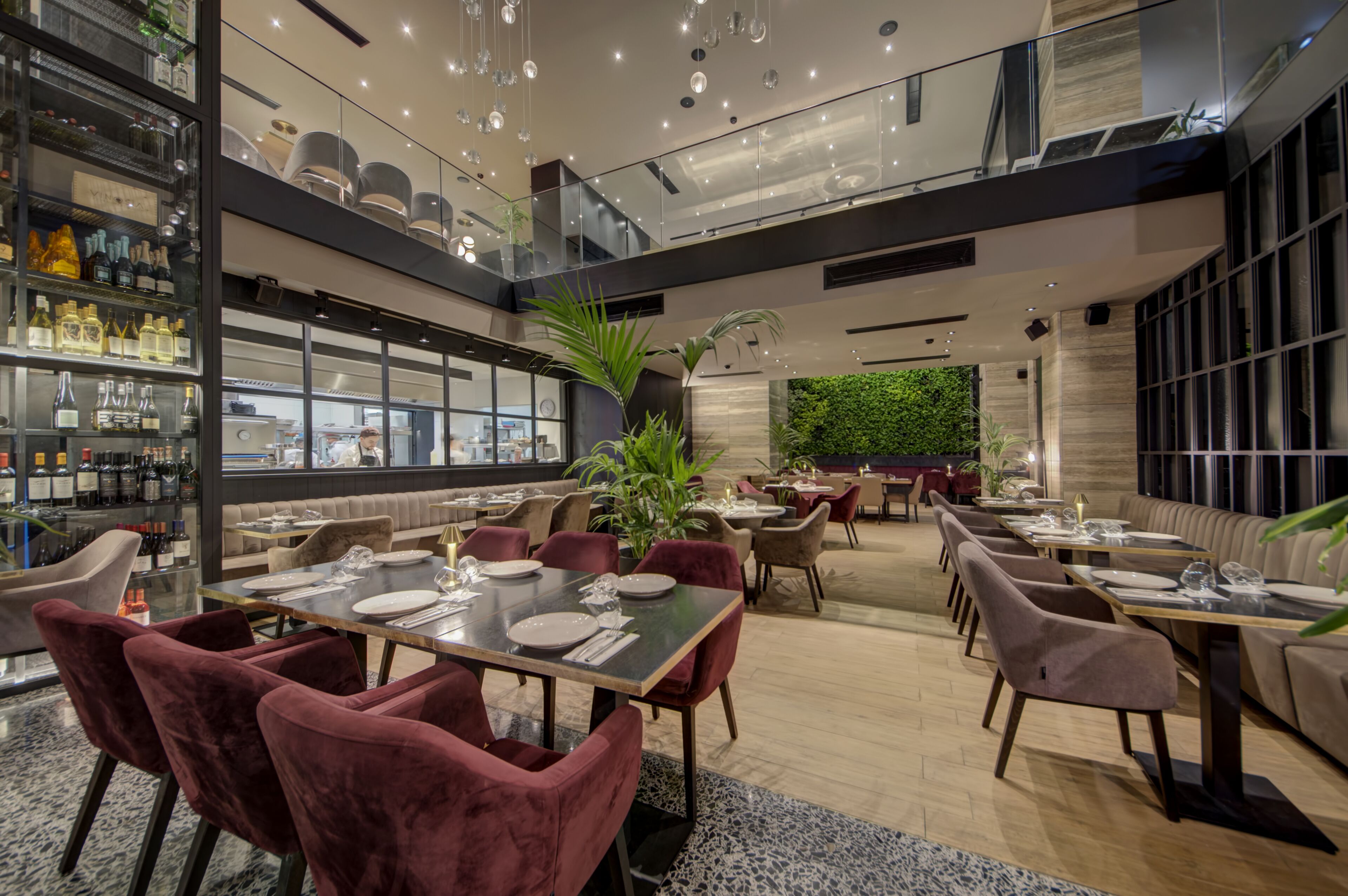 A modern restaurant with a high ceiling, glass walls, and a variety of seating options including tables and booths.