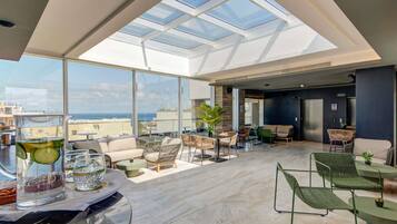 Un vaste salon sur le toit, doté d’une verrière, de mobilier moderne et offrant une vue sur la ville.