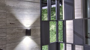 A modern interior with a wooden panel wall and a large window with a view of greenery. - Number 11 St Julian's Malta - Handwritten Collection (St. Julian's)
