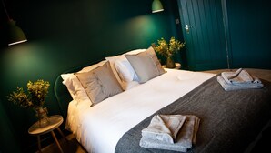 A neatly made bed with pillows, a bedside table with a vase, and a hanging light fixture. - Barber Shop Flat (Stockport)