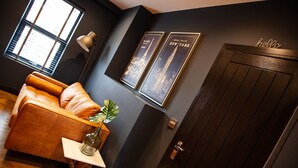 A modern interior with a leather sofa, a potted plant, and framed pictures of the Empire State Building. - Barber Shop Flat (Stockport)