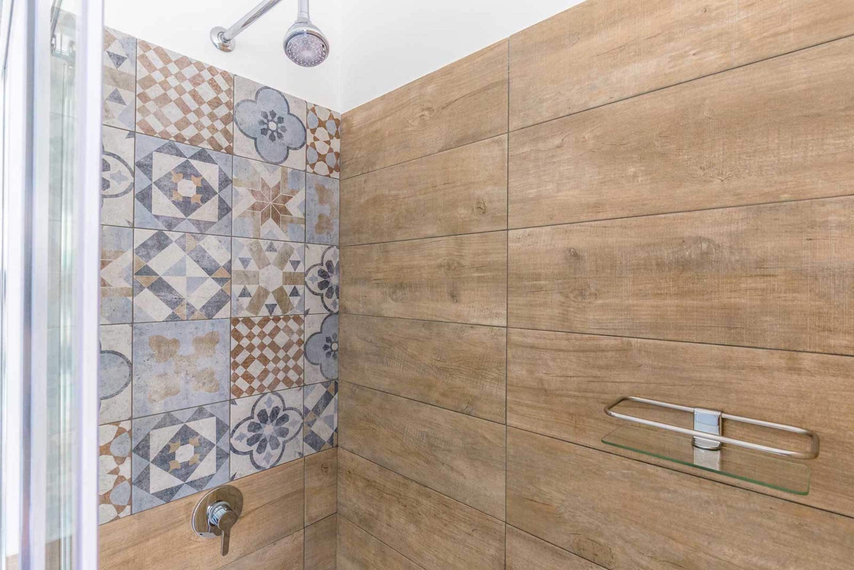 A shower area with a wooden panel wall and a tiled backsplash.