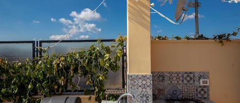 A rooftop patio with a grill, a sink, and a satellite dish.