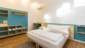A modern bedroom with a bed, wooden shelves, a desk, and a hanging light fixture. - Solemar Sicilia - Casa Colibrì (Santa Flavia)
