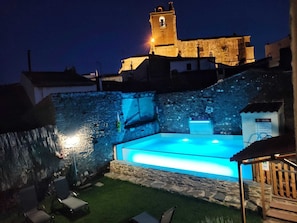 A swimming pool with a stone wall and a tower in the background.