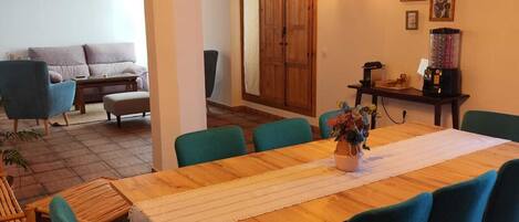 A dining area with a wooden table, teal chairs, and hanging light bulbs.