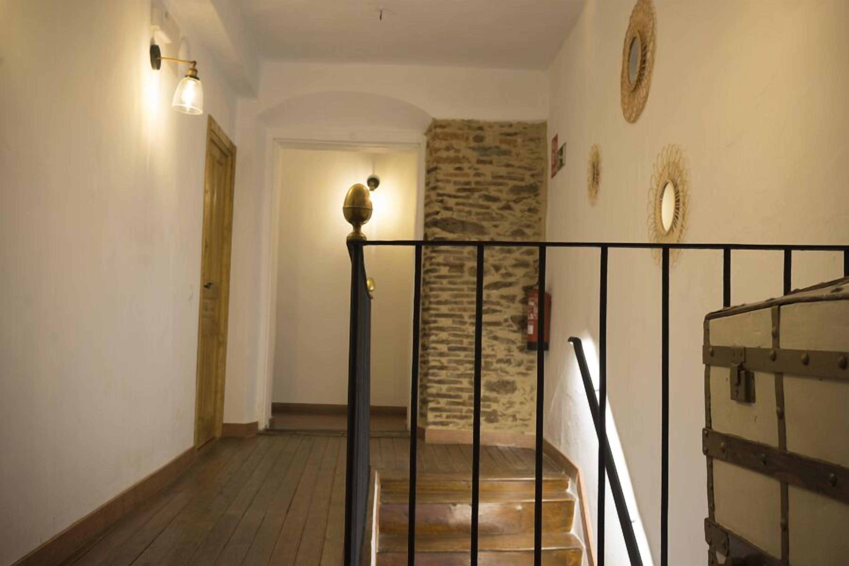 A staircase with a wooden handrail and a stone wall.