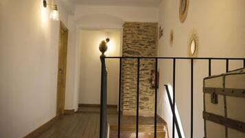 A staircase with a wooden handrail and a stone wall.