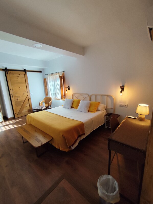 A bedroom with a bed, bedside table, lamp, chair, and a sliding door.