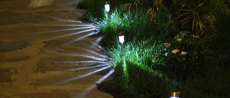 Un sendero bordeado de césped e iluminado por luces en el suelo.