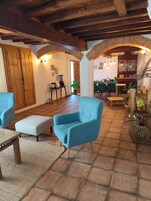 Una sala de estar acogedora con un sillón azul, una mesa de centro de madera y un comedor con sillas verdes.