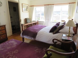 A bedroom with a bed, a nightstand, a chair, a dresser, and a window with curtains. - The Mill Restaurant & Accommodation (Dunfanaghy)