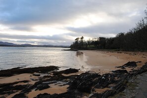 A rocky shoreline with a calm sea, distant mountains, and a cloudy sky. - The Mill Restaurant & Accommodation (Dunfanaghy)