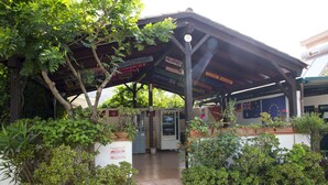 A covered outdoor area with a vending machine, a signboard with various destinations, and lush greenery.