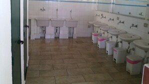 A public restroom with multiple sinks, a tiled floor, and a mirror on the wall.