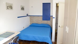 A small, neatly arranged bedroom with a bed, a desk, and a chair.