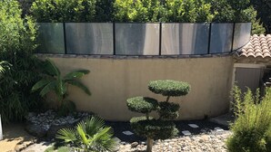 A landscaped garden with a variety of plants, a small tree, and a stone wall. - Duplex character cottage  (Grillon)