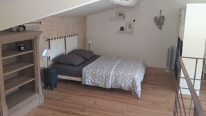 A bedroom with a bed, a nightstand, a dresser, and a shelf with decorative items. - Duplex character cottage  (Grillon)