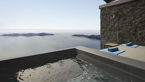 Un área de spa con pared de piedra, una bañera y toallas.
