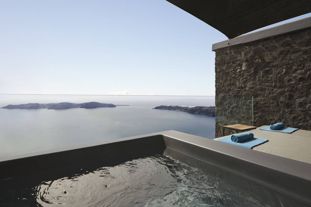 A spa area with a stone wall, a bathtub, and towels.
