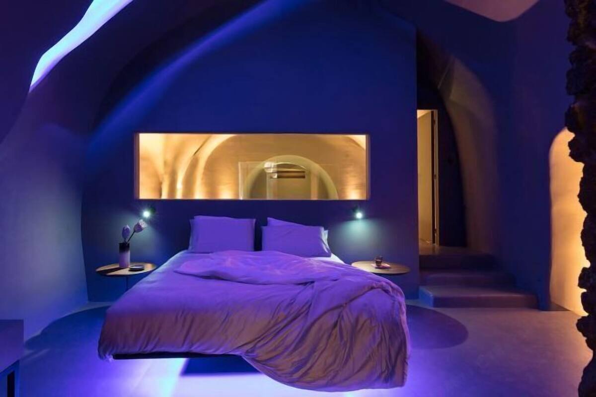A bedroom with a bed, a nightstand, and a wall-mounted light fixture.