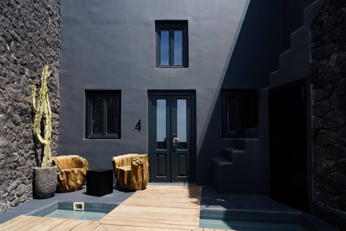 A modern building with a dark facade, two windows, and a door.