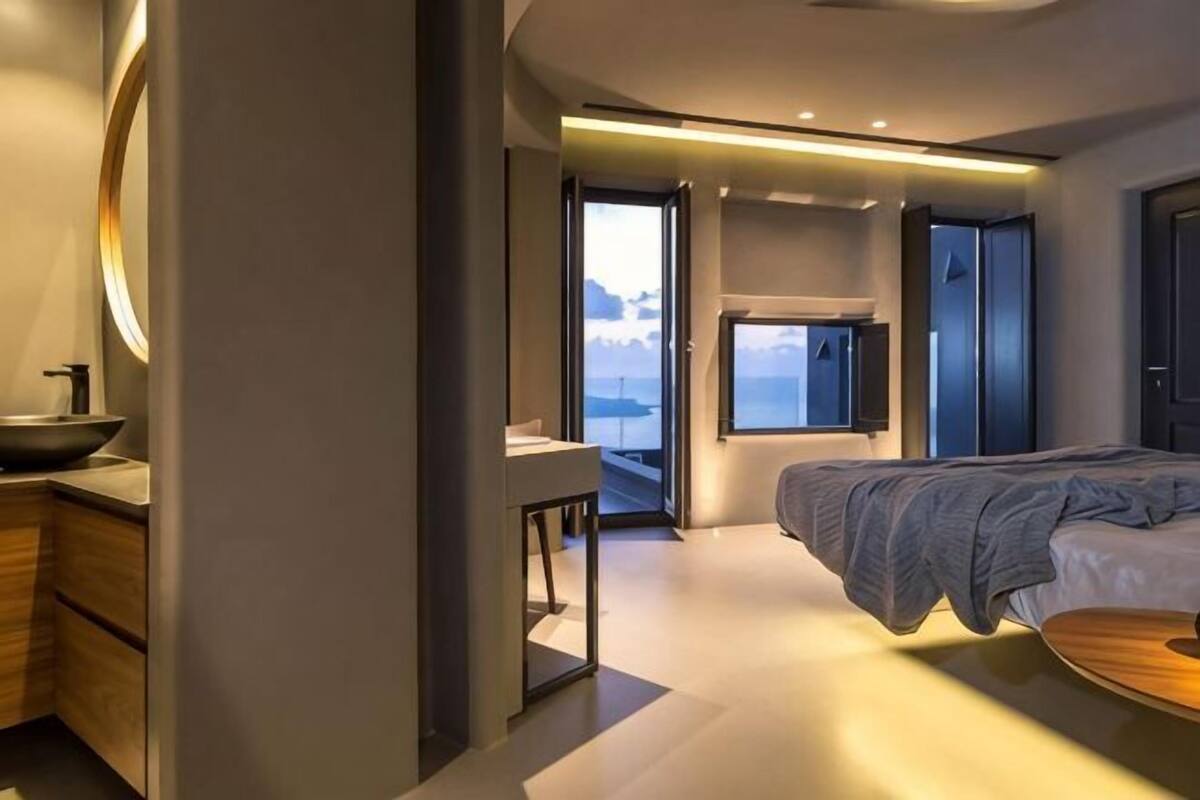 A modern bedroom with a bed, a bedside table, a window, and a view of the outdoors.