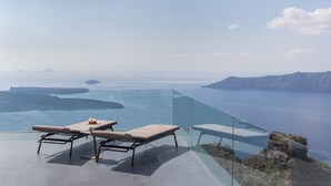 A glass infinity pool with lounge chairs and a table overlooking a scenic ocean view. - Kivotos Santorini - Preferred Hotels & Resorts (Santorini)