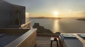 Un espacio de estar moderno al aire libre con vistas al mar y al atardecer.