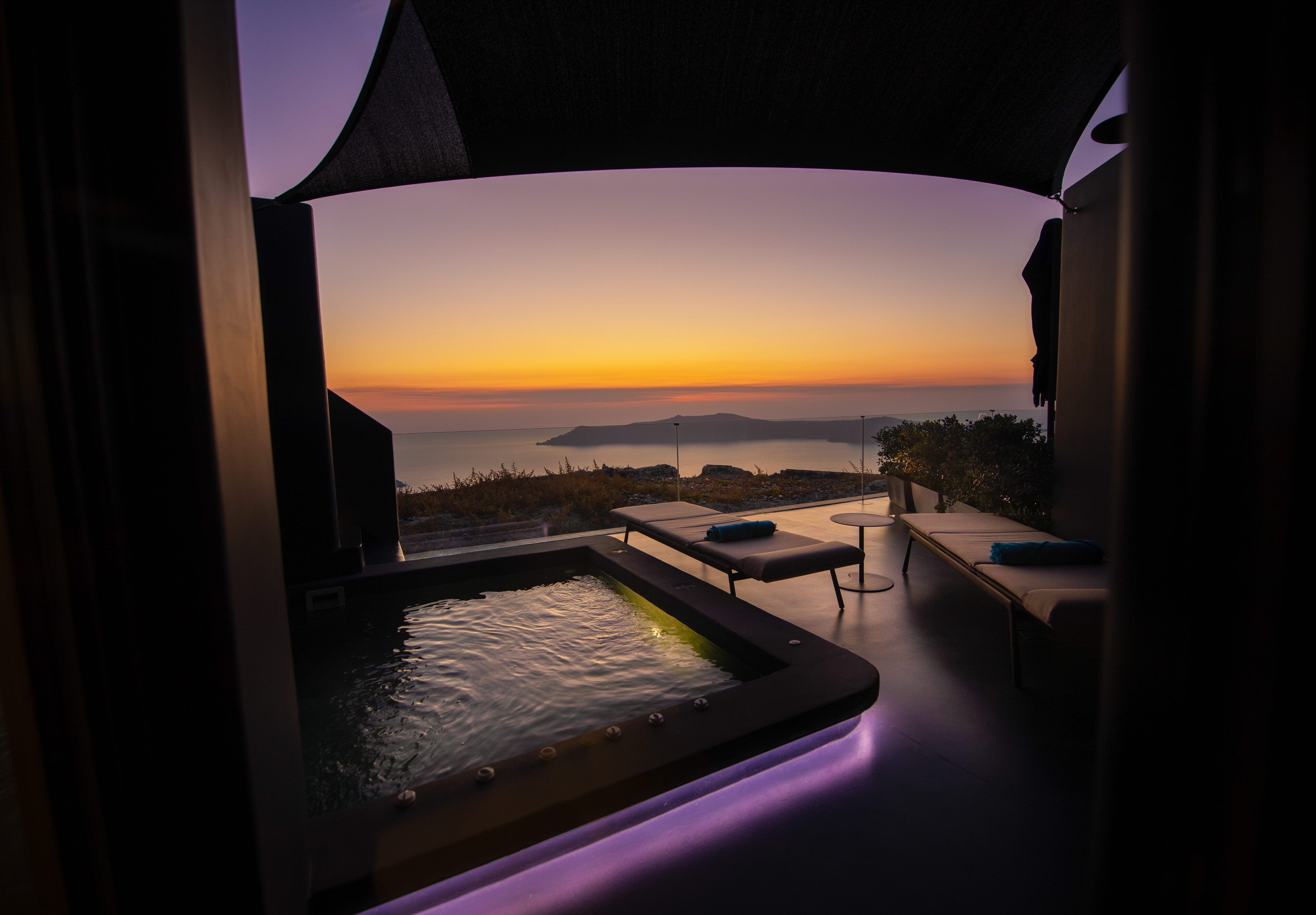 A hot tub with a sunset view, outdoor seating, and a poolside area.