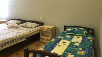 A bedroom with two single beds, each with a wooden headboard, a small bedside table, and a drawer.