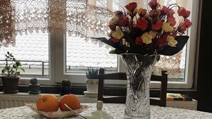A table with a floral tablecloth, a cup of coffee, a teapot, and a vase of flowers. - Mimino (Kutaisi)