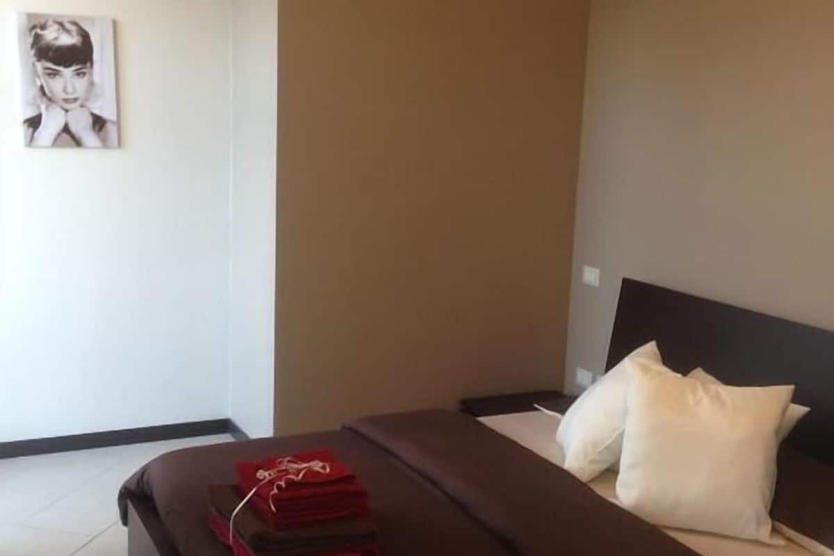 A hotel room with a bed, pillows, and a folded red garment on the bed.