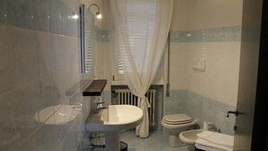 Un baño con lavamanos, inodoro, bidé y un espejo.