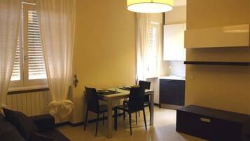 A compact living space with a dining area, a sofa, a lamp, and a kitchen area.