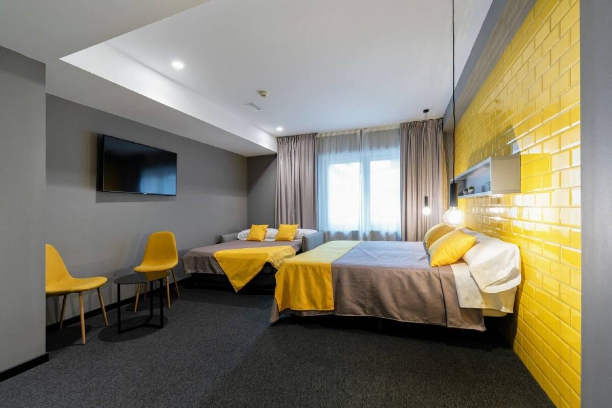 Ein Hotelzimmer mit zwei Betten, einem Fernseher, einem Schreibtisch und einem Stuhl.