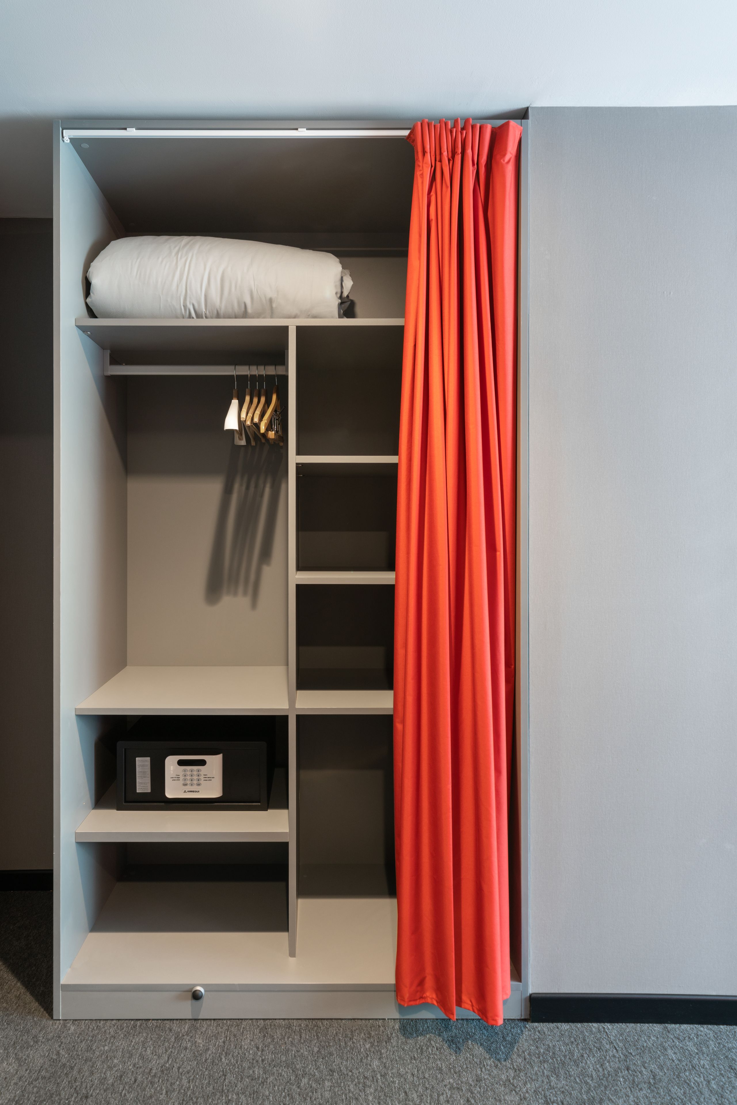 Un dressing accessible sans porte, doté d’étagères ouvertes, d’une tringle et d’un lit escamotable.