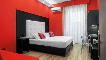 Ein modernes Hotelzimmer mit einem großen Bett, einem Nachttisch, einem Sessel und einem Schreibtisch mit einem Computer.