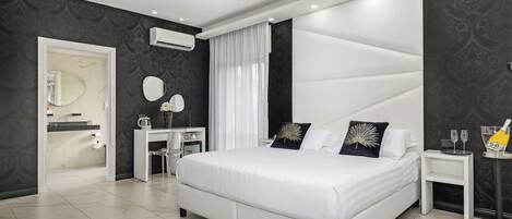 Un dormitorio moderno con una cama grande, una mesita de noche con lámpara y una pequeña mesita con una botella y vasos.