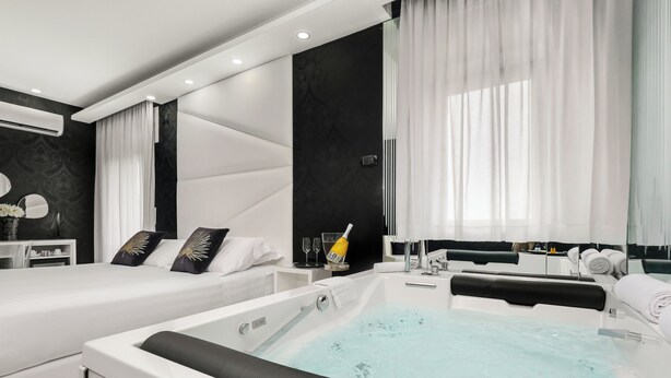 Una habitación de hotel moderna con dos camas, una bañera grande y un tocador con espejo.