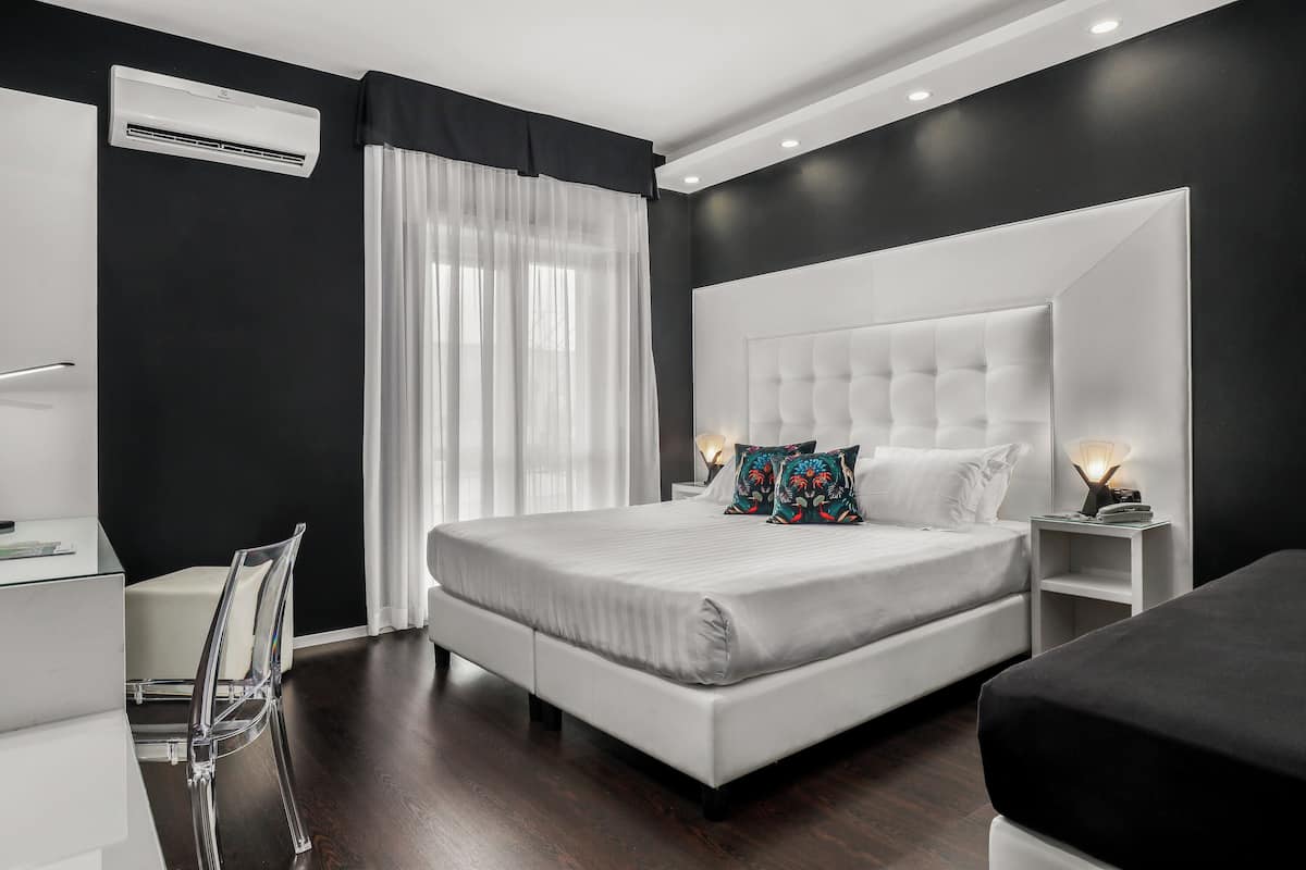 A modern bedroom with a large bed, bedside tables, a desk, and a chair.