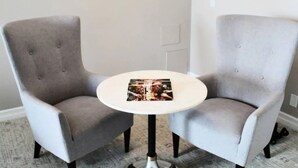 Dos sillones grises con una pequeña mesa redonda en medio, mostrando una revista sobre la mesa.