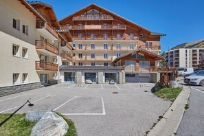 Ein mehrstöckiges Hotel mit Balkonen, einem Parkplatz und einer Stein-Fassade.