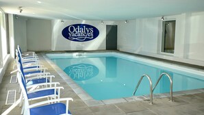 A swimming pool with lounge chairs and a sign reading "Odaly's vacancies". - Appartement abordable | Accès piscine intérieure (Les Deux Alpes)